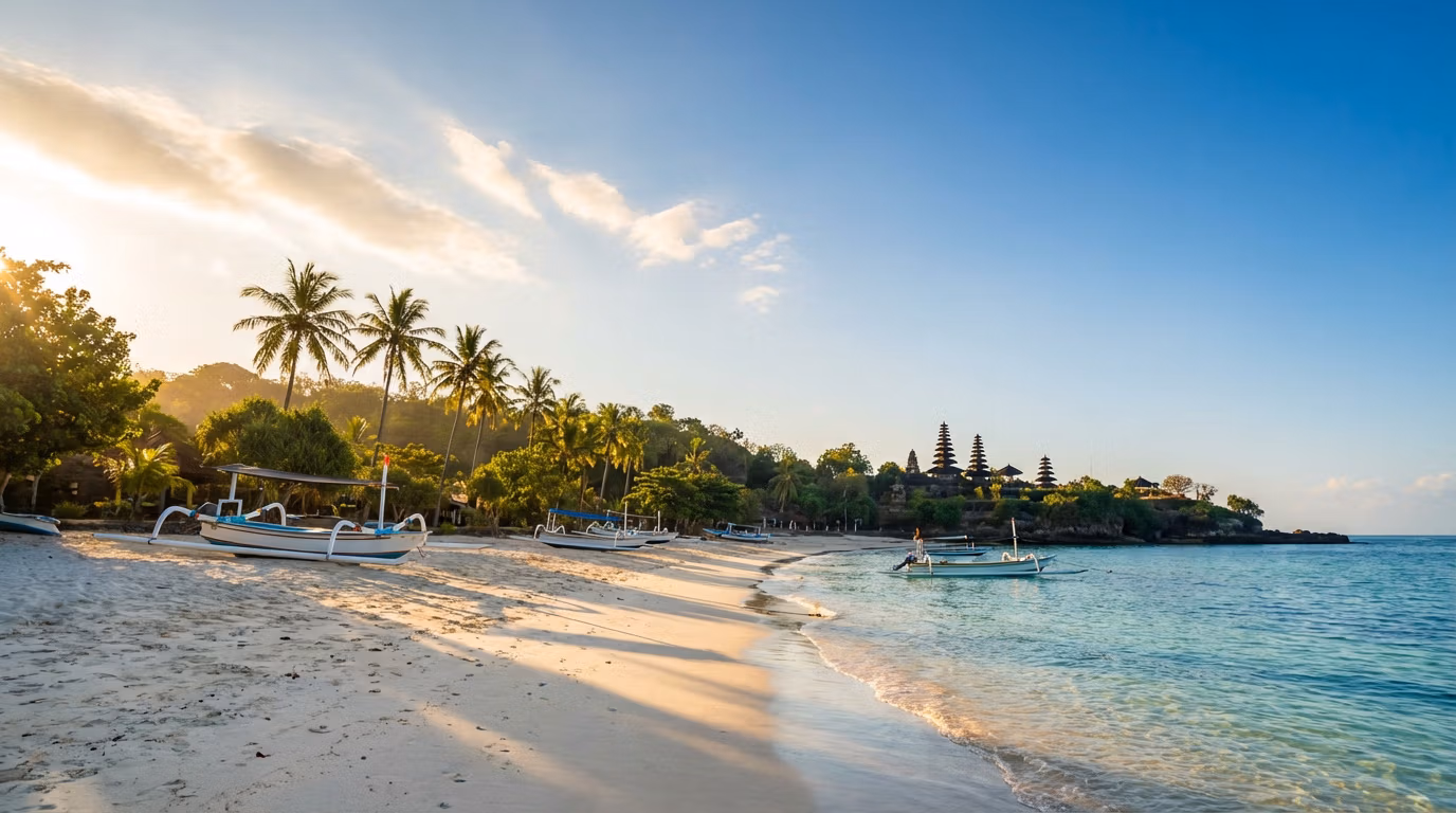 Plage paradisiaque de Bali au lever du soleil et ses temples Plage de sable blanc à Bali au lever du soleil avec des bateaux traditionnels, palmiers et temples Meru en arrière-plan.